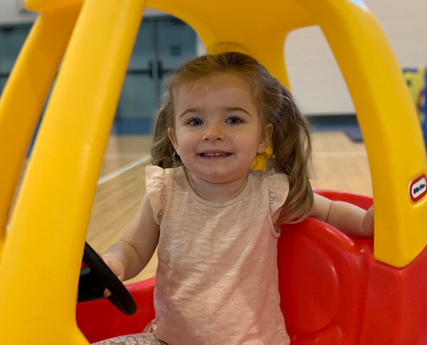 Young girl plays in yellow and red car